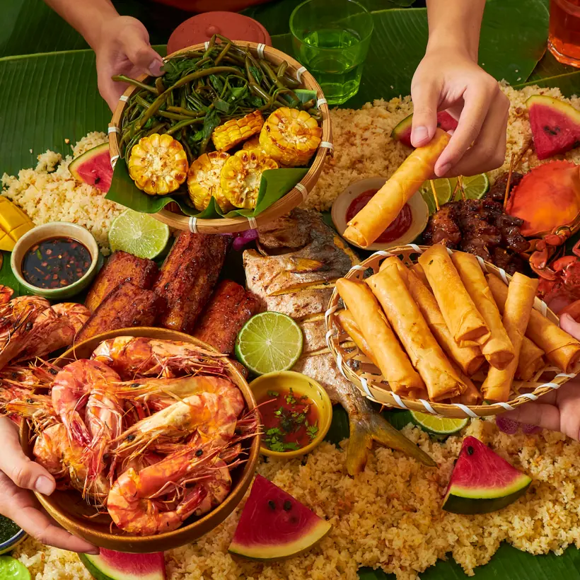 Overhead shot of a shared seafood feast with prawns, spring rolls, grilled fish and rice at a restaurant